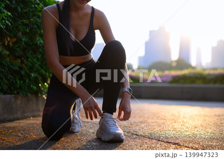 Cropped shot fitness, woman tying shoe for running preparation, workout or training exercise with water bottle 139947323
