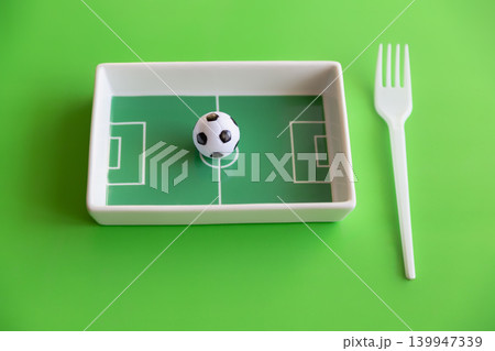 Small soccer ball on football field plate with fork on bright green sports nutrition concept. 139947339