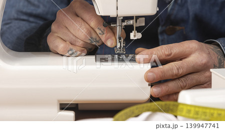 Person's hands threading a modern sewing machine needle Person's hands threading a modern sewing machine needle 139947741