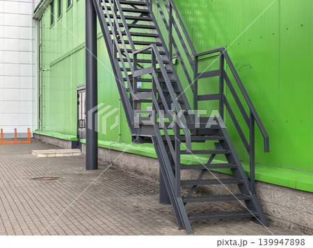 Metal fire escape staircase on green industrial building exterior 139947898