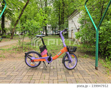 Purple and Orange Sharing Electric Bicycle Parked on Path Purple and Orange Sharing Electric Bicycle Parked on Path 139947912