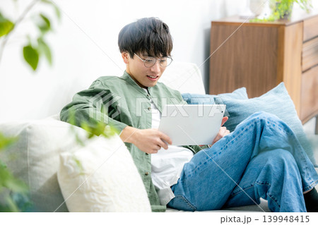 リビングでタブレットを見る男性 リビングでタブレットを見る男性 139948415