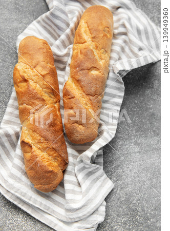 Freshly baked baguettes resting on striped kitchen towel 139949360