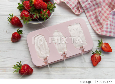 Preparing homemade strawberry yogurt popsicles on wooden table Preparing homemade strawberry yogurt popsicles on wooden table 139949377