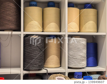 Industrial yarn cones in beige gray and blue on factory storage shelves 139949607