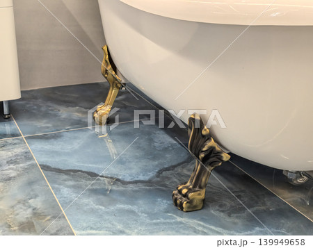 Antique brass clawfoot bathtub legs detail on glossy blue marble floor tiles Antique brass clawfoot bathtub legs detail on glossy blue marble floor tiles 139949658