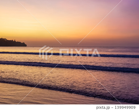 Twilight sky with yellow and purple gradient over ocean waves at Jimbaran Beach, Bali, Indonesia Twilight sky with yellow and purple gradient over ocean waves at Jimbaran Beach, Bali, Indonesia 139949909