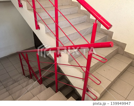 Concrete staircase with bright red metal railing in apartment building Concrete staircase with bright red metal railing in apartment building 139949947