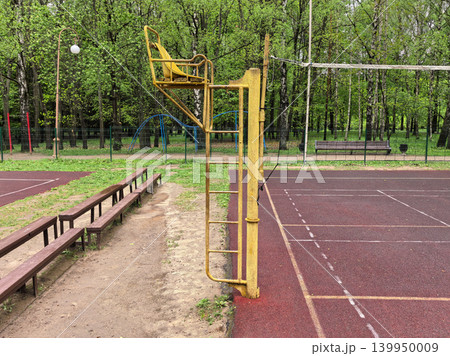 Empty outdoor volleyball court with yellow referee chair in green park 139950009