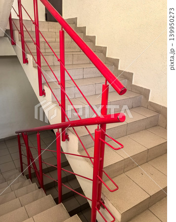 Red metal staircase railing in residential building stairwell vertical view Red metal staircase railing in residential building stairwell vertical view 139950273