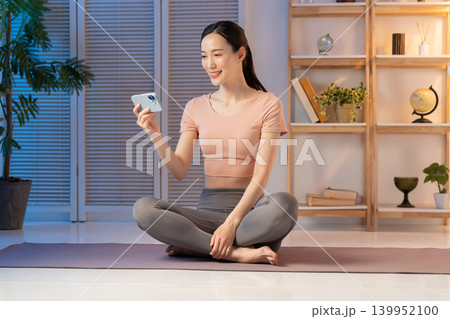 夜スマホを見るヨガウェアの女性 夜スマホを見るヨガウェアの女性 139952100