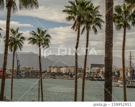 Palm Trees Framing a Coastal Harbor Malaga City Waterfront With Mountains and Boats Under Cloudy Sky Palm Trees Framing a Coastal Harbor Malaga City Waterfront With Mountains and Boats Under Cloudy Sky 139952951