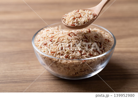 Organic Thai brown rice in a glass bowl with wooden spoon, Asian food ingredient Organic Thai brown rice in a glass bowl with wooden spoon, Asian food ingredient 139952980