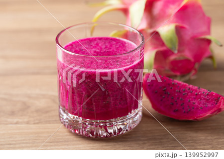 Glass of red dragon fruit smoothie on wooden background, Healthy tropical summer drink Glass of red dragon fruit smoothie on wooden background, Healthy tropical summer drink 139952997