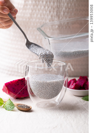 Woman's hands preparing chia pudding with fresh dragon fruit in a glass, healthy eating concept Woman's hands preparing chia pudding with fresh dragon fruit in a glass, healthy eating concept 139953008