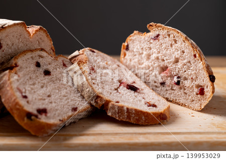 Sliced cranberry sourdough bread on cutting wooden board with black background Sliced cranberry sourdough bread on cutting wooden board with black background 139953029