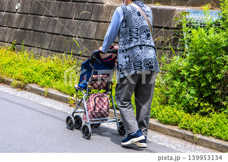 日本の横浜都市景観右側を歩くカートの高齢女性。蒸し暑いが、マスク姿…人生とは…＝横浜市内で 139953134