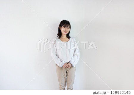 白い背景の前でカメラ目線で微笑む日本人の若い女性 139953146