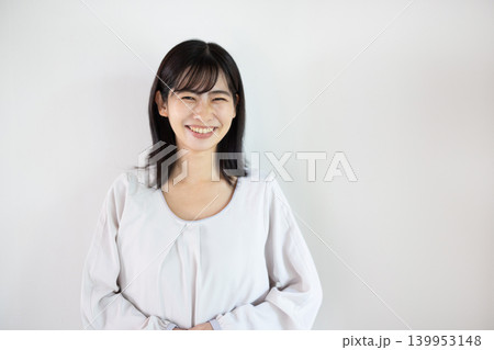 白い背景の前でカメラ目線で微笑む日本人の若い女性 白い背景の前でカメラ目線で微笑む日本人の若い女性 139953148