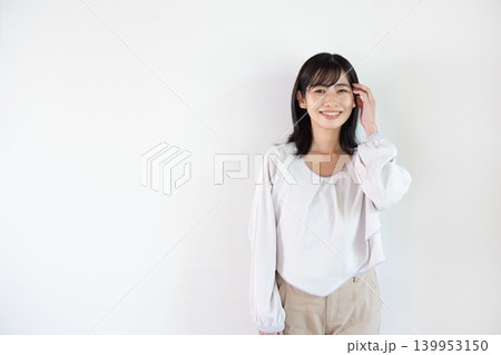 白い背景の前でカメラ目線で微笑む日本人の若い女性 白い背景の前でカメラ目線で微笑む日本人の若い女性 139953150