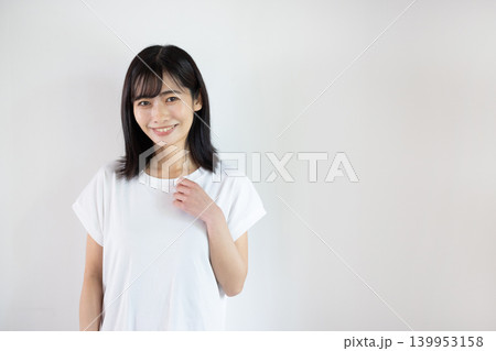 白い背景の前でカメラ目線で微笑む日本人の若い女性 白い背景の前でカメラ目線で微笑む日本人の若い女性 139953158