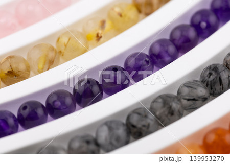 Amethyst gemstone bead strands close up on white tray Amethyst gemstone bead strands close up on white tray 139953270