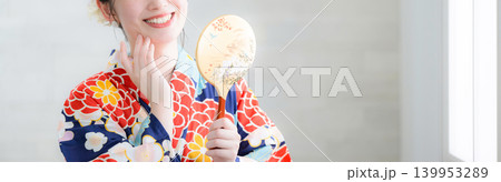 浴衣で鏡をを持って身だしなみを気にする笑顔の女性、夏祭りや日本文化イメージ上半身顔無しのバナー 139953289