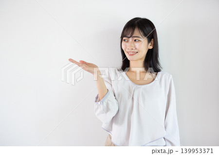 白い背景の前で手のひらを差し出し微笑む日本人の若い女性 139953371
