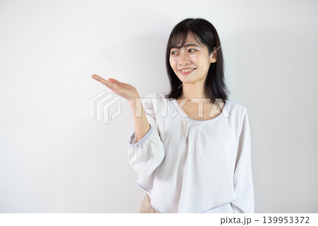 白い背景の前で手のひらを差し出し微笑む日本人の若い女性 139953372