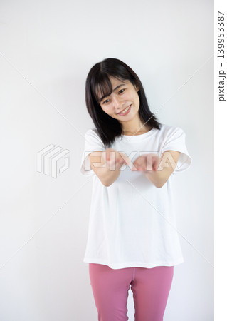 白い背景の前で手のひらを差し出し微笑む日本人の若い女性 白い背景の前で手のひらを差し出し微笑む日本人の若い女性 139953387