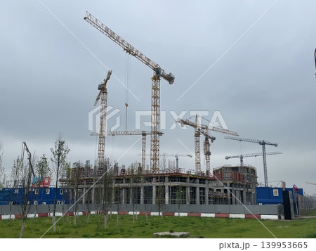 Construction site with multiple cranes and building in progress on a cloudy day Construction site with multiple cranes and building in progress on a cloudy day 139953665