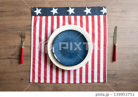 Patriotic table setting with american flag placemat and blue plate on wooden table Patriotic table setting with american flag placemat and blue plate on wooden table 139953751