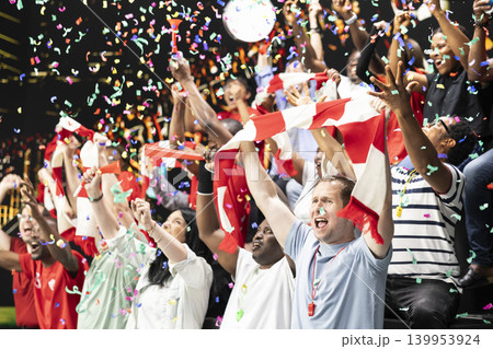 Soccer supporters celebrating victory with confetti, raised scarves and cheering crowd in stadium stands after dramatic live football match and team spirit. Authentic fan euphoria as world champions. Soccer supporters celebrating victory with confetti, raised scarves and cheering crowd in stadium stands after dramatic live football match and team spirit. Authentic fan euphoria as world champions. 139953924