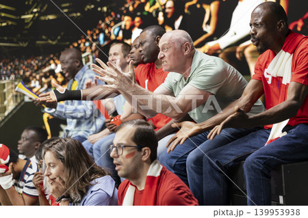 Red team football supporters showing mixed emotions in packed stadium stands during tense live soccer match, scarves, horns and crowd reactions. Upset fans in shock, football defeat frustration. Red team football supporters showing mixed emotions in packed stadium stands during tense live soccer match, scarves, horns and crowd reactions. Upset fans in shock, football defeat frustration. 139953938