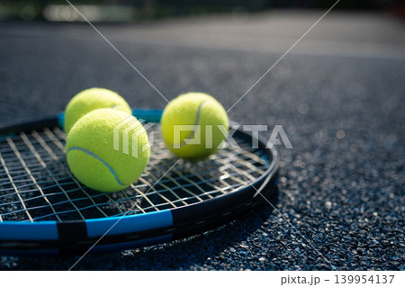 Tennis balls on racket on blue court close up 139954137