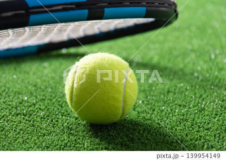 Tennis ball on green court with racket close up background 139954149