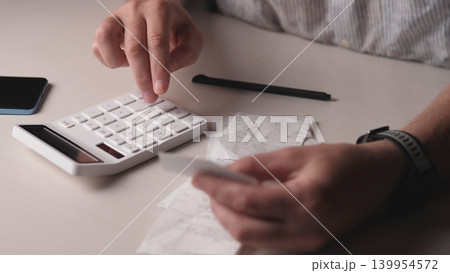 Closeup Hands Pressing Calculator Keys, Crumpled Receipts Scattered On Desk, Pencil And Phone Beside, Wristwatch Visible, Freelancer Tracking Expenses And Totals With Focused Tension 139954572