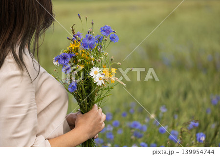 Woman Holding Wildflower Bouquet in Cornflower Field 139954744