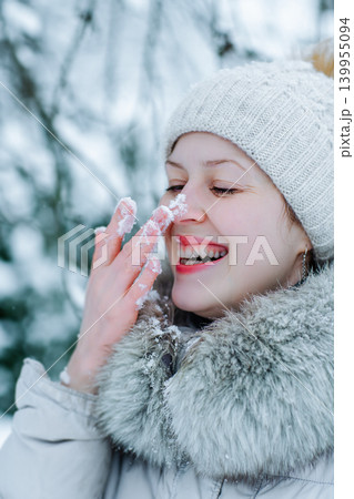 Portrait of young happy woman in warm winter clothing with snow on nose Portrait of young happy woman in warm winter clothing with snow on nose 139955094