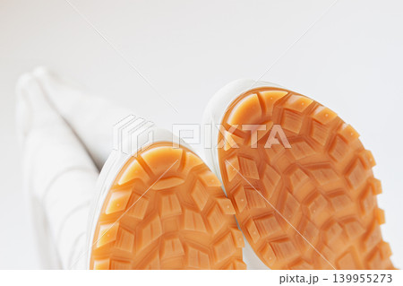 Bottom view of demi season boots with orange rubber sole and tread pattern shown close up, white background. Rain boots protection, waterproof footwear, grip, traction, autumn weather, product mockup 139955273