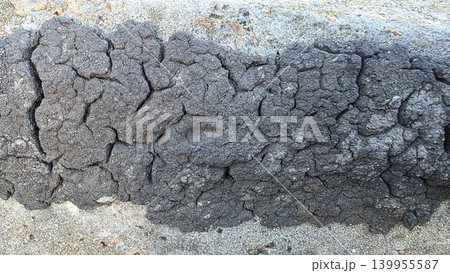 Dark volcanic rock texture with cracked rough surface, natural stone background for geology, abstract design and rugged outdoor themes. Dark volcanic rock texture with cracked rough surface, natural stone background for geology, abstract design and rugged outdoor themes. 139955587