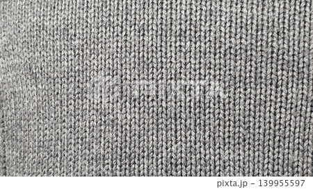 Gray knitted fabric texture background with tight woven stitches, soft textile surface for clothing, design and cozy winter themes. Gray knitted fabric texture background with tight woven stitches, soft textile surface for clothing, design and cozy winter themes. 139955597