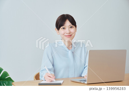 ノートを取りながらオンラインで仕事をする女性 139956283