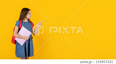 Schoolgirl with backpack and notebook pointing at copy space on yellow background Schoolgirl with backpack and notebook pointing at copy space on yellow background 139957281
