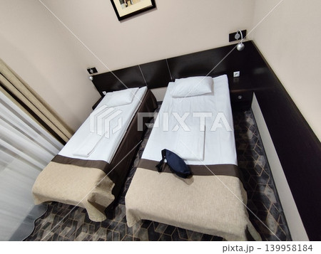 Simple standard hotel room interior featuring two single twin beds Simple standard hotel room interior featuring two single twin beds 139958184