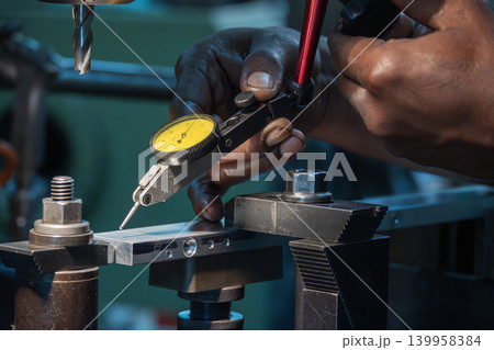 Close-up of a machine operator setting up a dial test indicator for precise workpiece alignment on a milling machine. 139958384