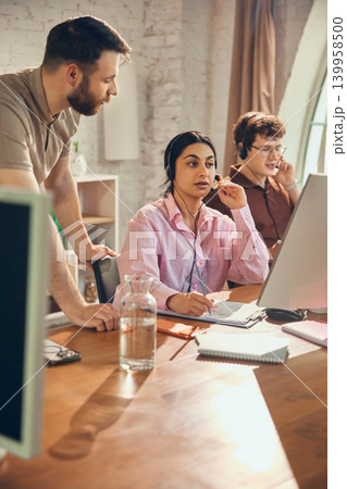 Helpdesk agent taking notes while speaking with customer. Helpdesk agent taking notes while speaking with customer. 139958500