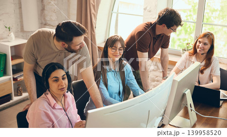 Office support team reviewing customer service tasks near computers. Office support team reviewing customer service tasks near computers. 139958520