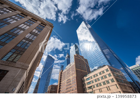 New york, usa august 20,2024. Skyscrapers and modern office buildings reflecting a sunny blue sky with clouds, highlighting urban development and business in manhattan 139958873