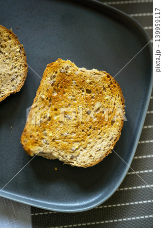 Whole grain seeded toast slices on dark plate, healthy breakfast food concept Whole grain seeded toast slices on dark plate, healthy breakfast food concept 139959117